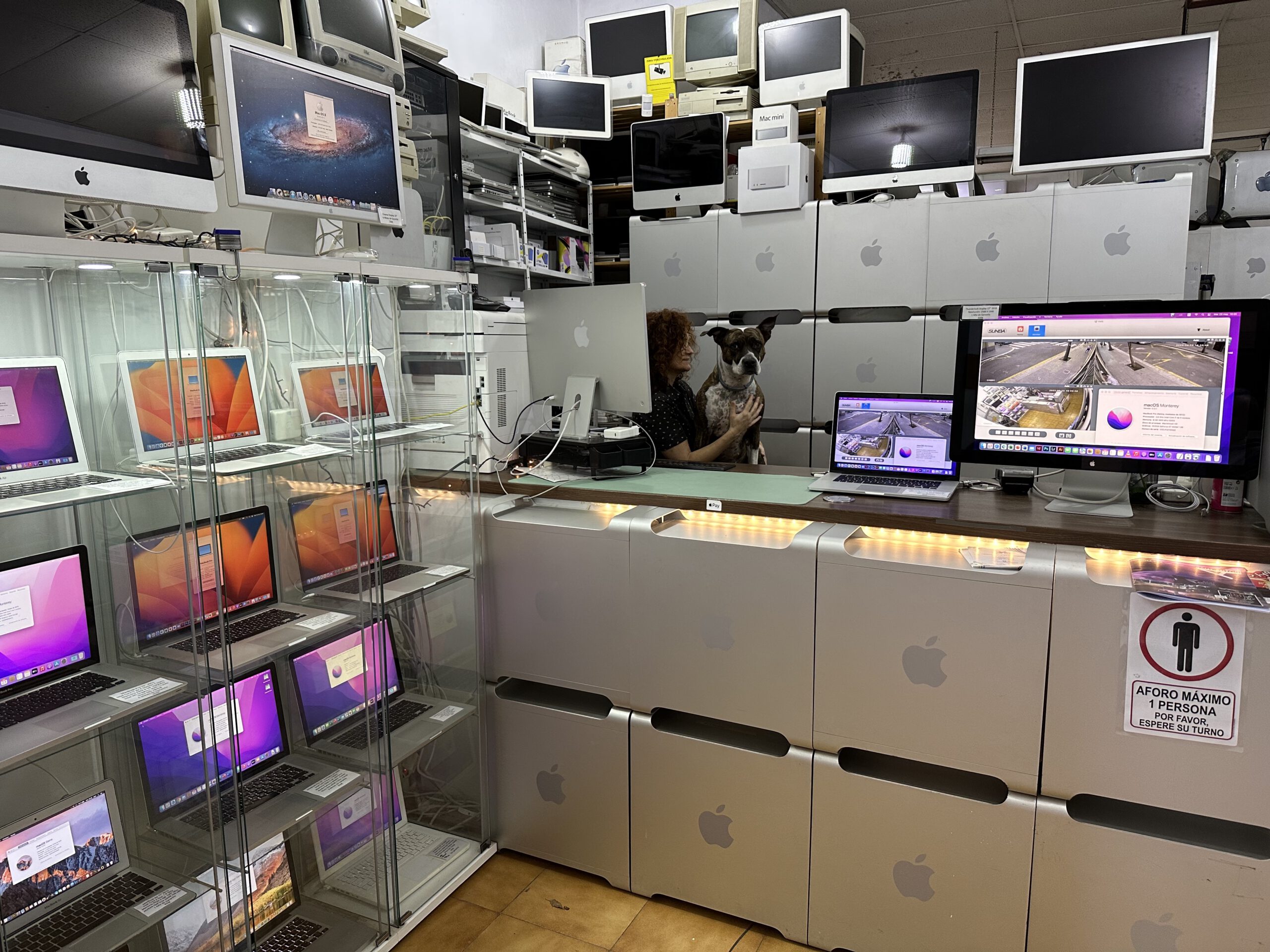Interior de la tienda ReciclaTecnologia en Creu dels Molers, Barcelona, con Macs y la perra Piña en el mostrador