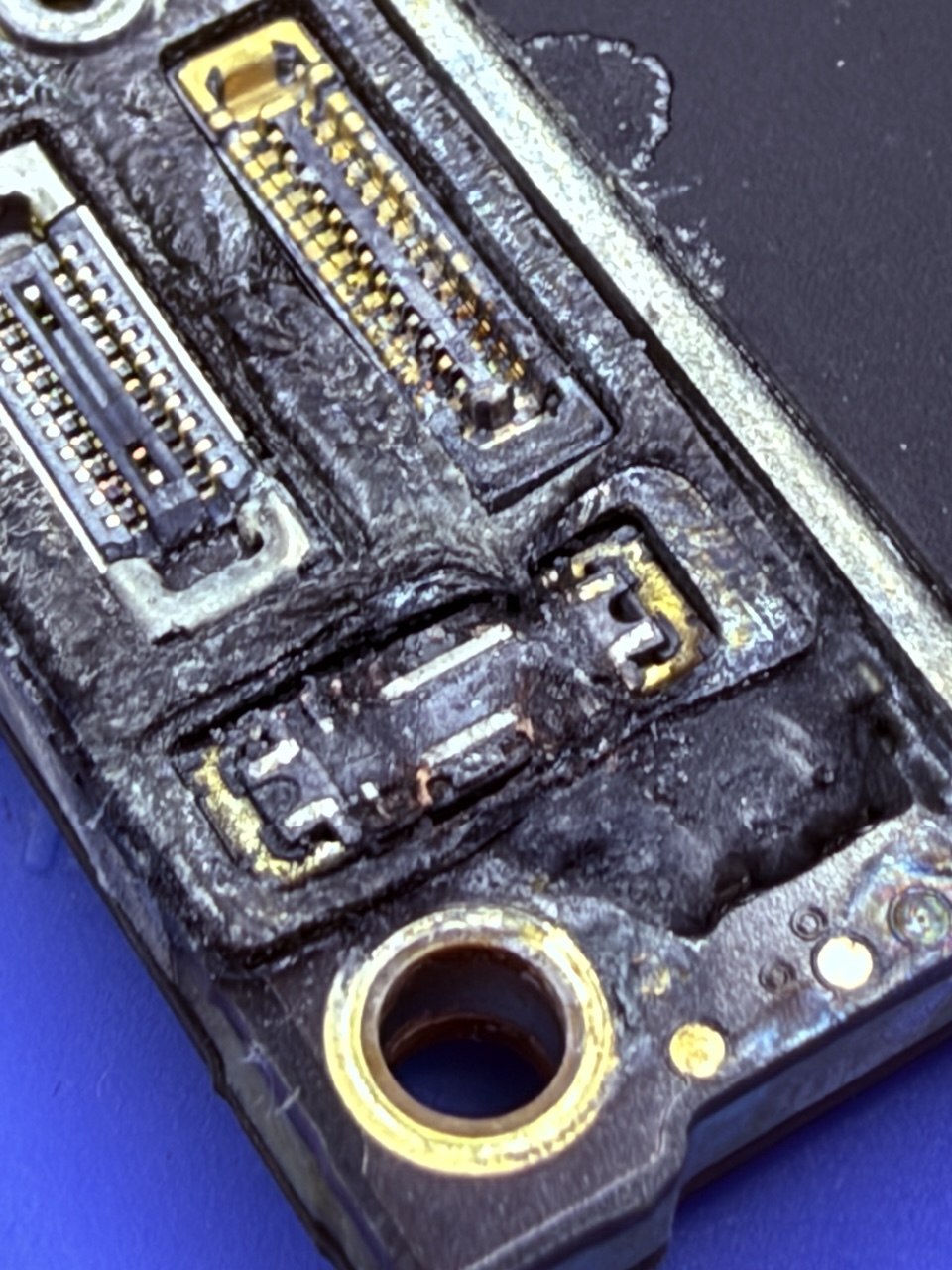 Corrosión avanzada en la placa de un iPhone por agua de mar, vista al microscopio