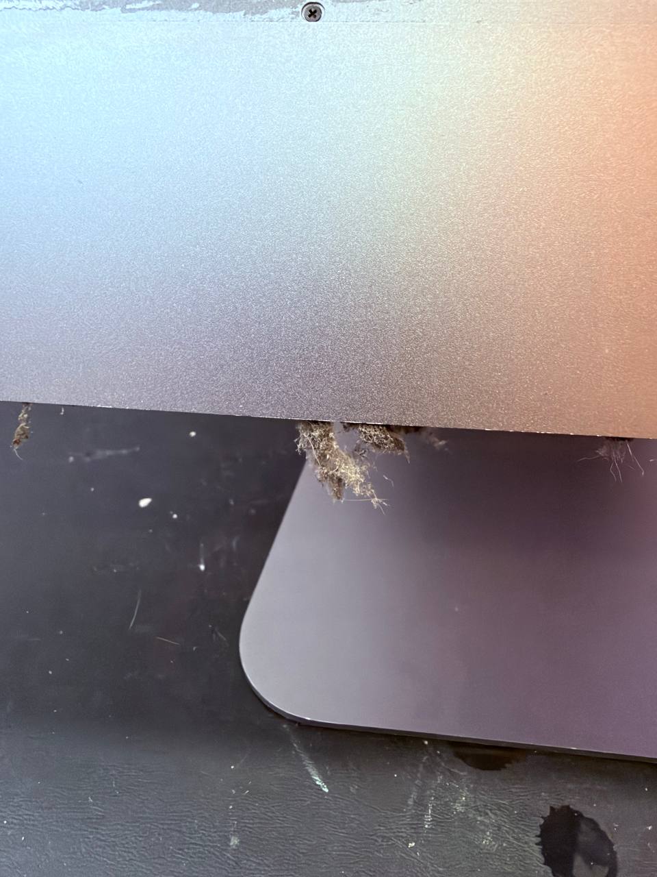 Rendijas inferiores de un iMac Pro 2017 obstruidas por polvo y pelusa antes de la limpieza