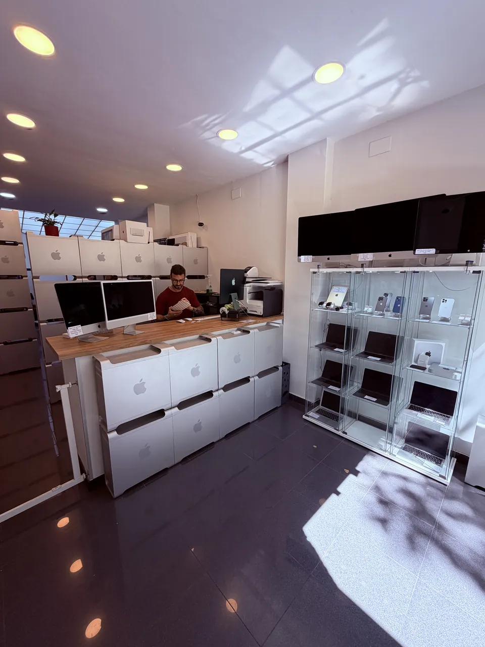 Técnico de ReciclaTecnologia trabajando en el mostrador, con el stock propio visible desde la tienda