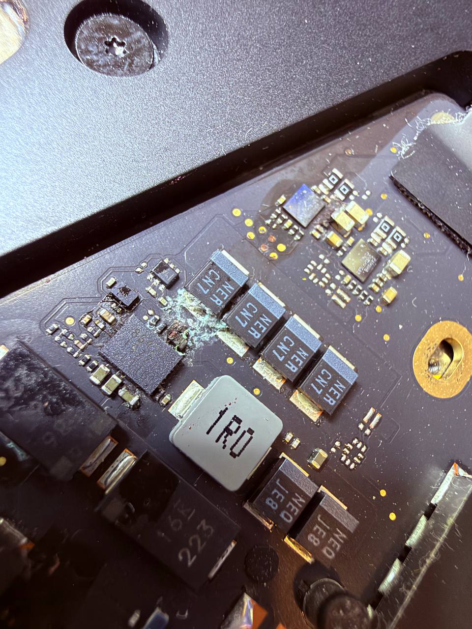 Detalle real de corrosión y residuos en la placa lógica de un MacBook Pro M2 mojado