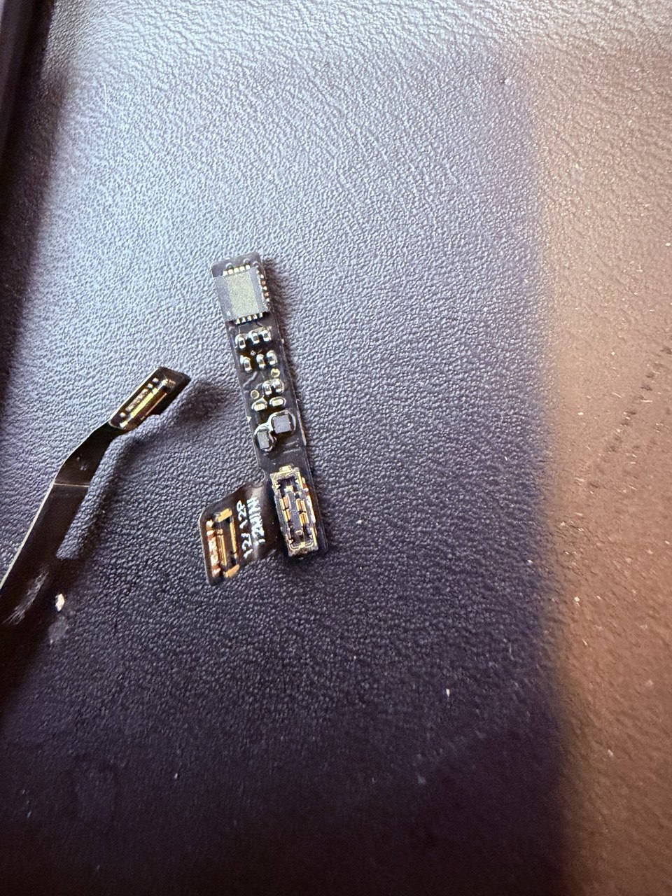 Chip interposer soldado en una batería falsa de iPhone para clonar la autenticación de Apple