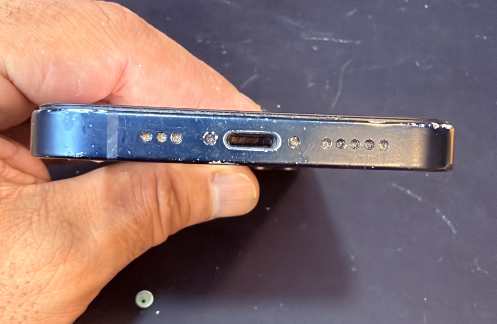 Borde inferior de un iPhone con el conector de carga Lightning visto de cerca en el taller