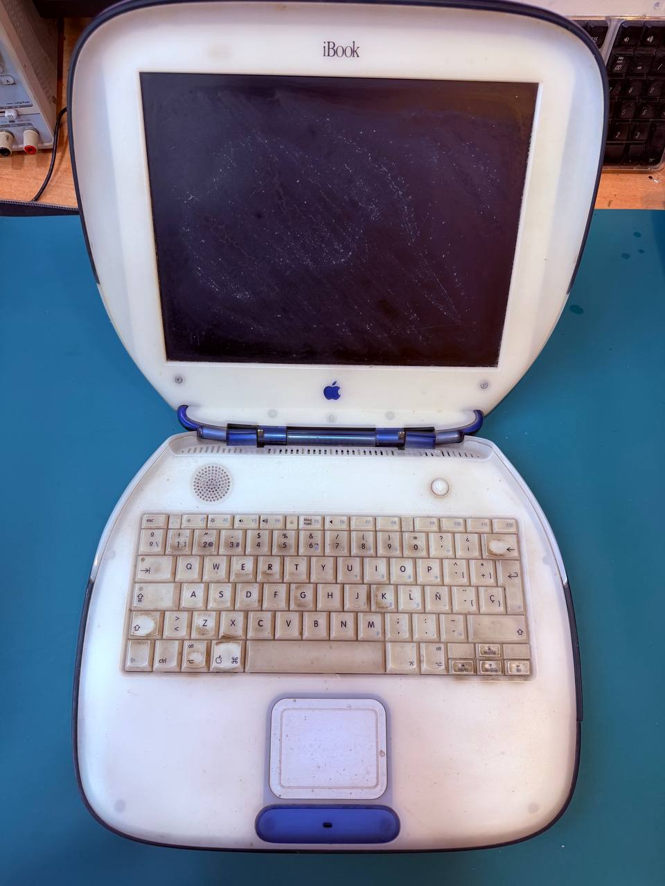 iBook G3 Clamshell azul abierto sobre la mesa del taller de ReciclaTecnología