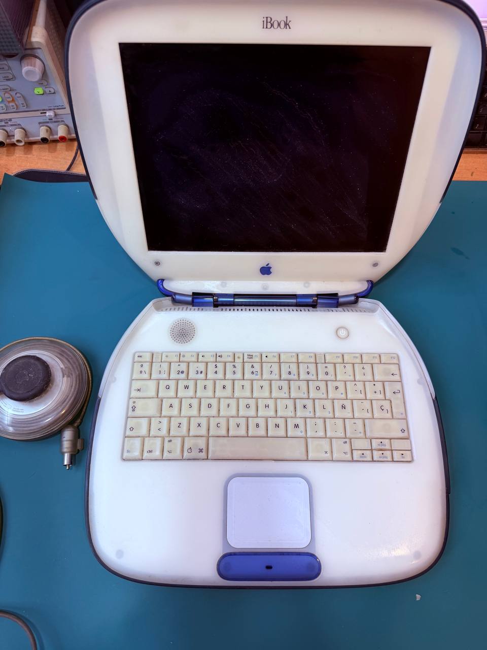 Frontal del iBook G3 Clamshell azul con teclado español y pantalla apagada