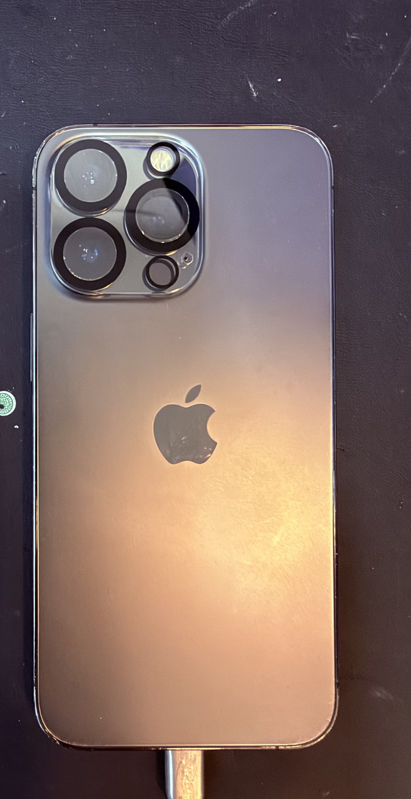Trasera de un iPhone 13 Pro grafito sobre la alfombrilla de trabajo del taller