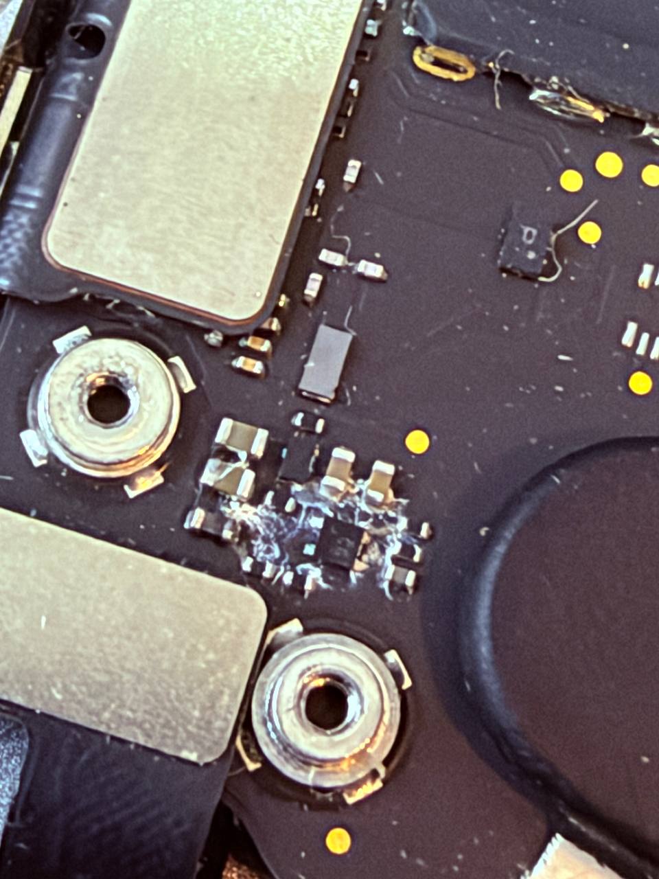 Daño por líquido en placa base MacBook — componentes con residuo cristalizado