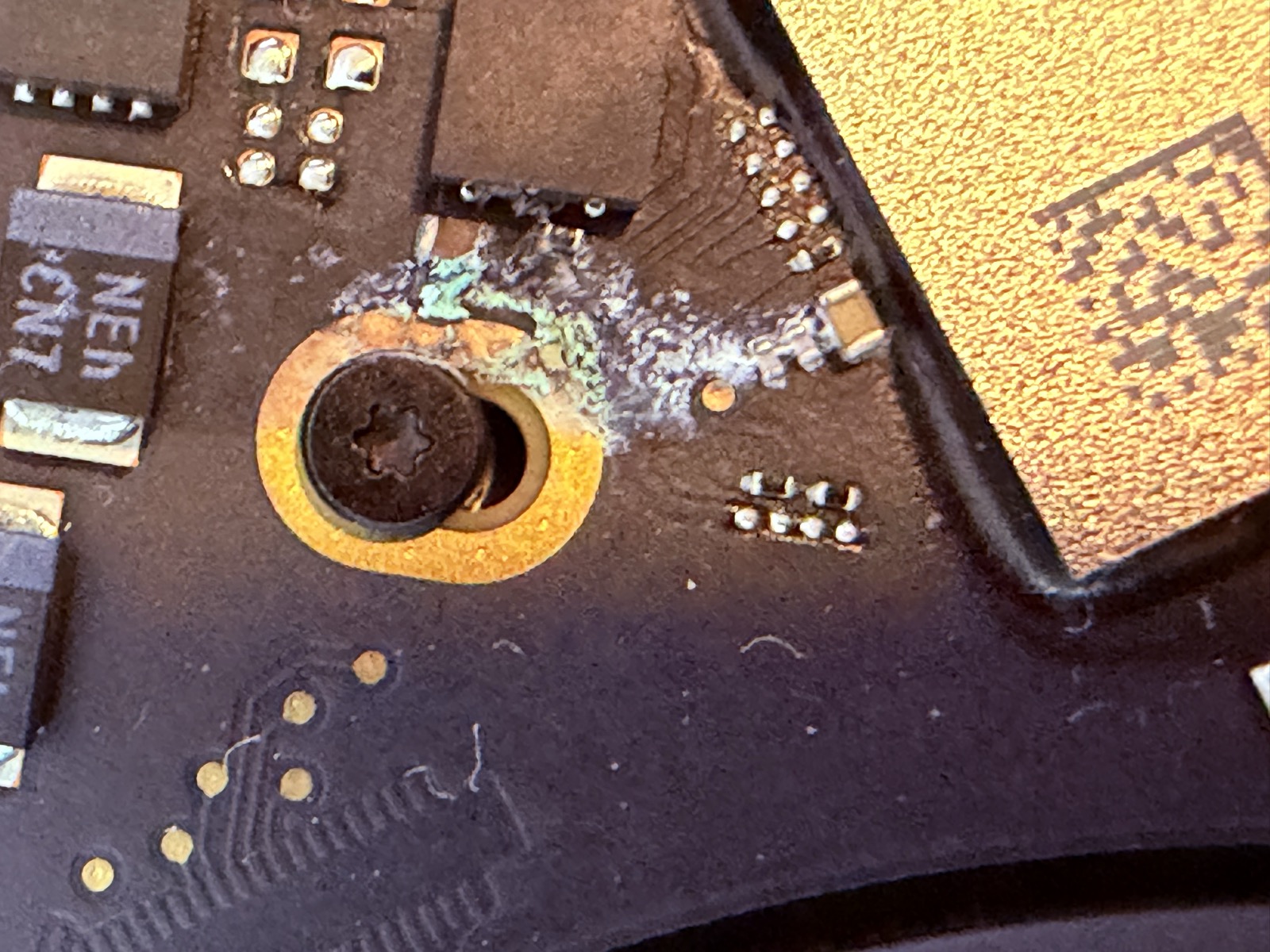 Oxidación de cobre (verde) alrededor de un tornillo de la placa base MacBook