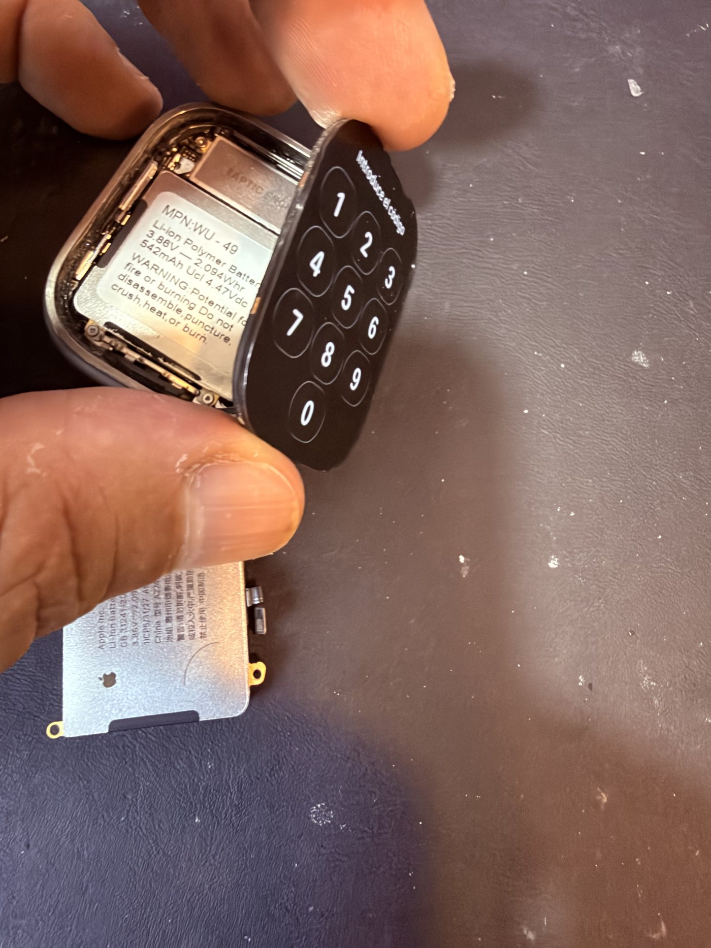 Cambio de batería de un Apple Watch en el taller de ReciclaTecnologia en Barcelona: el reloj abierto con la batería original a la vista y la batería Apple de recambio sobre la mesa