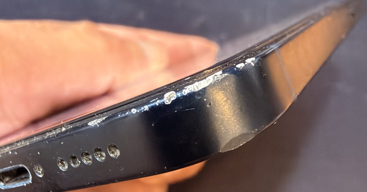 Borde inferior de un iPhone de segunda mano con marcas de uso alrededor del conector de carga y el chasis original de fábrica
