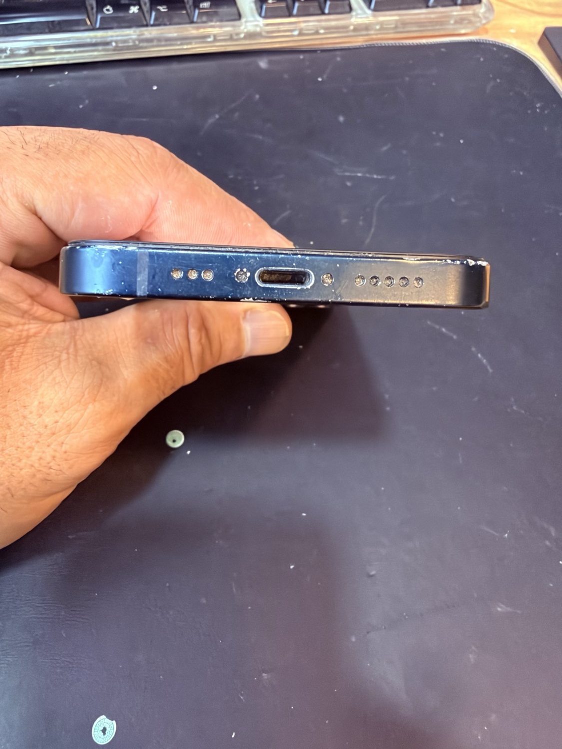 Los dos tornillos junto al conector de carga de un iPhone, intactos