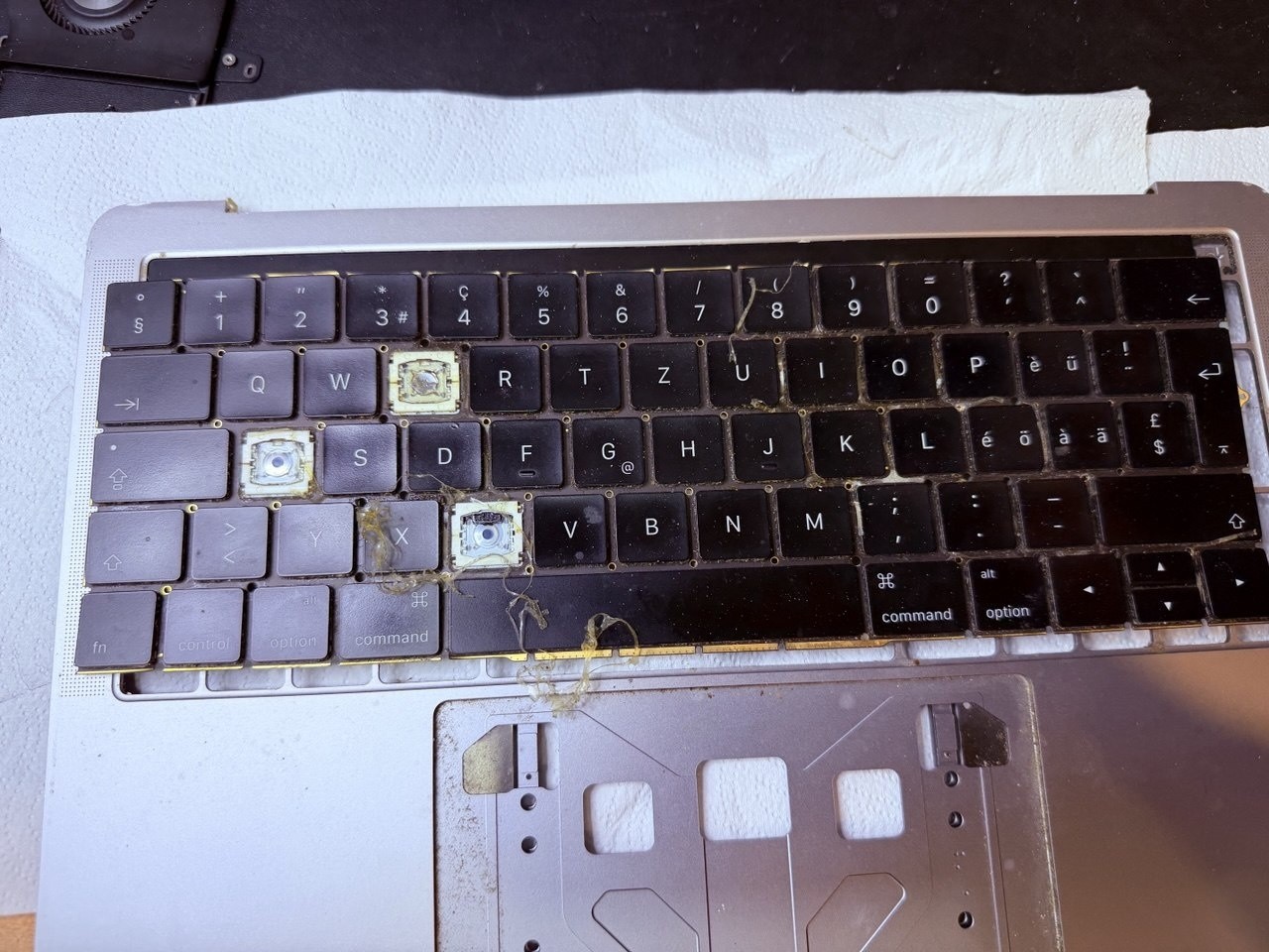 Teclado de un MacBook Pro retirado del equipo, con varias teclas ausentes y restos de suciedad